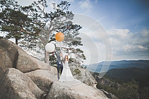 Happy wedding couple kissing and hugging near a high cliff