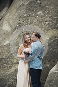 Happy wedding couple kissing and hugging near a high cliff