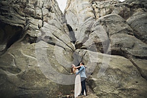 Happy wedding couple kissing and hugging near a high cliff