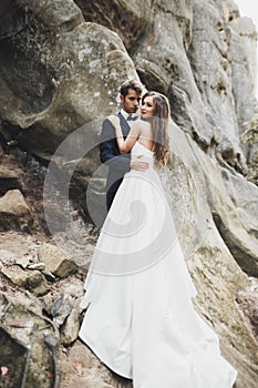 Happy wedding couple kissing and hugging near a high cliff