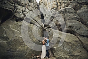 Happy wedding couple kissing and hugging near a high cliff