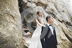 Happy wedding couple kissing and hugging near a high cliff