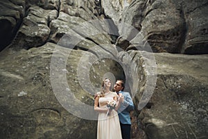 Happy wedding couple kissing and hugging near a high cliff