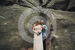 Happy wedding couple kissing and hugging near a high cliff