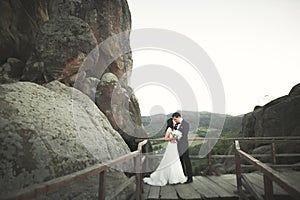 Happy wedding couple kissing and hugging near a high cliff