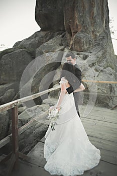 Happy wedding couple kissing and hugging near a high cliff