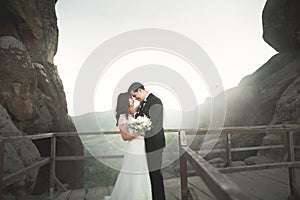 Happy wedding couple kissing and hugging near a high cliff