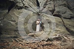 Happy wedding couple kissing and hugging near a high cliff