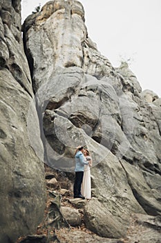 Happy wedding couple kissing and hugging near a high cliff