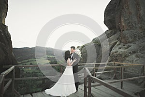 Happy wedding couple kissing and hugging near a high cliff