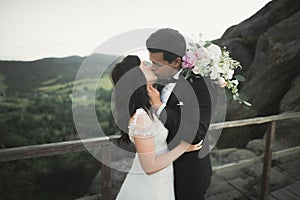 Happy wedding couple kissing and hugging near a high cliff