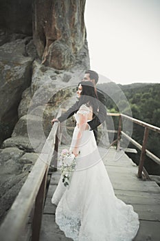 Happy wedding couple kissing and hugging near a high cliff