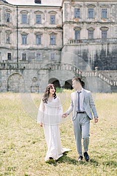 Happy wedding couple standing and walking near old ancient castle