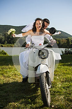 Happy wedding couple take a ride in a white motorcycle.