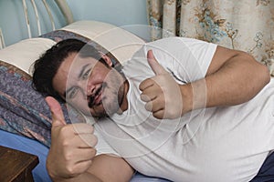 A happy and well rested man gives a double thumbs up after a good night's sleep. A comfortable single size bed