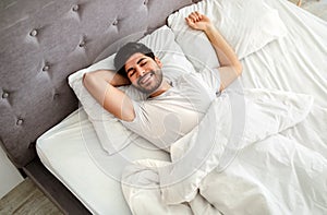 Happy wellslept arab guy waking up in the morning, awakening after good sleep