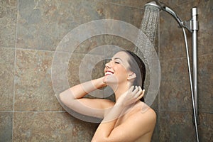 Happy wet woman under water enjoying shower