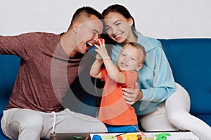 Happy white family enjoy and play at home. Mom, dad and son laugh