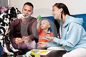 happy white family is happy and playing at home with a Dalmatian dog