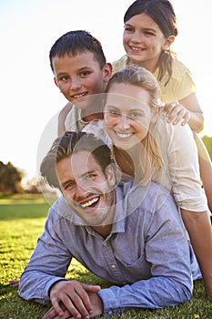 Happy white family lying in a pile on grass outdoors
