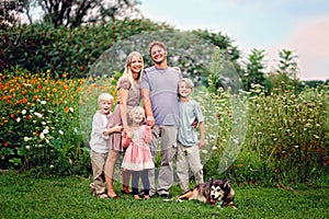 Happy Wholesome Caucasian Family and Dog Smiling and Posing by Flowers photo