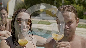 Happy wife and husband drinking cocktails in swimming pool