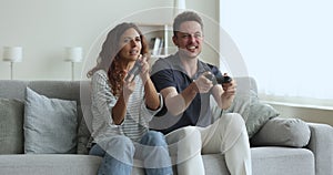 Happy wife and husband playing video game together at home