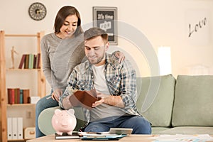 Happy wife near husband with salary indoors. Money savings concept