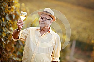 Happy winegrower tasting wine in vineyard