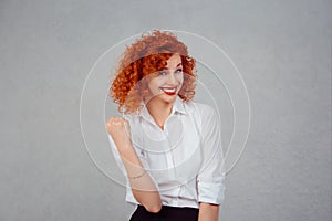 Happy winner. Closeup half body portrait redhead curly woman in white formal shirt exults pumping fists ecstatic celebrates