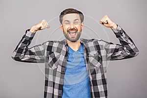 Happy winner! Happy young handsome man gesturing and keeping mouth open while standing against grey gray white background