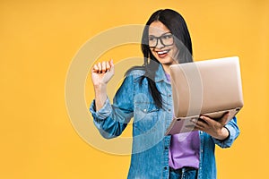 Happy winner! Portrait of attractive surprised excited smiling business woman with laptop, isolated over yellow background,