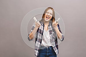 Happy winner! Portrait of a playful young woman with long hair holding bunch of money banknotes and looking at camera, copy space