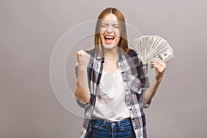 Happy winner! Portrait of a playful young woman with long hair holding bunch of money banknotes and looking at camera, copy space