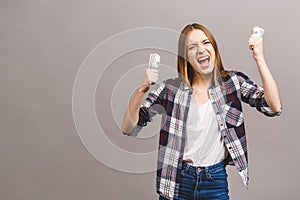 Happy winner! Portrait of a playful young woman with long hair holding bunch of money banknotes and looking at camera, copy space