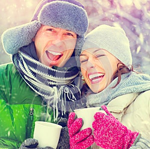 Happy winter couple with hot drinks outdoors