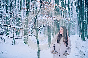 Happy Winter Girl. Portrait of a young woman in snow trying to warm herself. Beautiful girl in the winter forest in