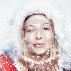 Happy winter woman blowing snowflakes