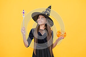 Happy witch kid with magic wand and pumpkin jack o lantern wear costume of wizard on halloween party, halloween miracle