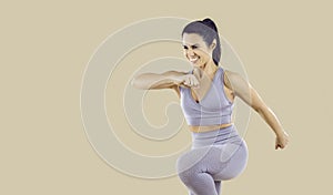 Happy woman in activewear doing fitness exercise isolated on beige copy space background