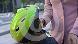 Happy woman admiring daughter in bike helmet outdoors stroking child face, love