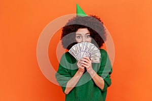 Happy woman with Afro hairstyle wearing green casual style sweater holding covering half of mouth