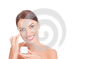 Happy woman applying cream on face