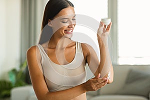 Happy Woman Applying Moisturizer Jar Enjoying Skincare At Home