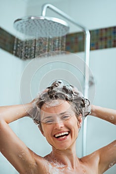 Happy woman applying shampoo in shower photo