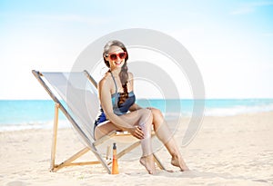 Happy woman applying sun block while sitting in beach chair