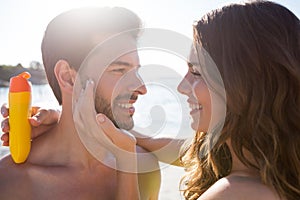 Happy woman applying sunscream on man face at beach