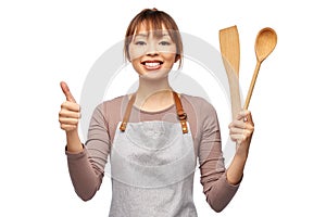 happy woman in apron with wooden spoon and spatula