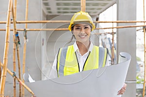 Happy woman architect home builder project manager work in construction site with blueprint floor plan looking camera smiling