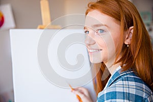 Happy woman artist making sketches on canvas in art class